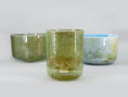 Load image into Gallery viewer, Enchanted Forest 3 bowl harmonised set of Alchemy Crystal Tones Quartz Singing Bowls. Three bowls with green and blue hues on a light grey background.