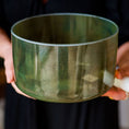 Load image into Gallery viewer, Person holding a green crystal sound bowl with a blurred background
