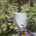 Load image into Gallery viewer, Light blue crystal sound healing bowl in a natural setting with green grass and purple flowers.