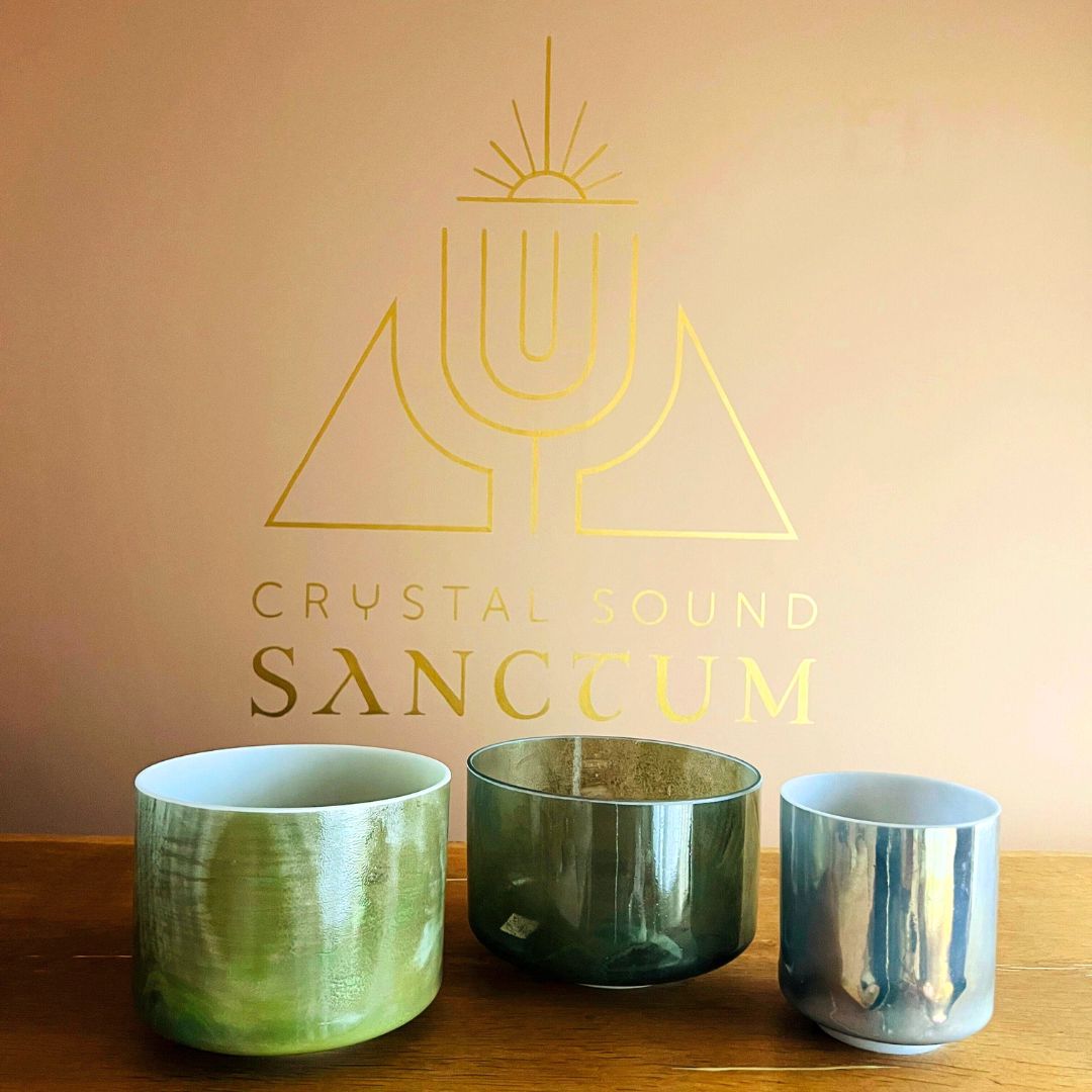 Three Crystal Sound Bowls on a wooden surface with 'Crystal Sound Sanctum' logo in the background.