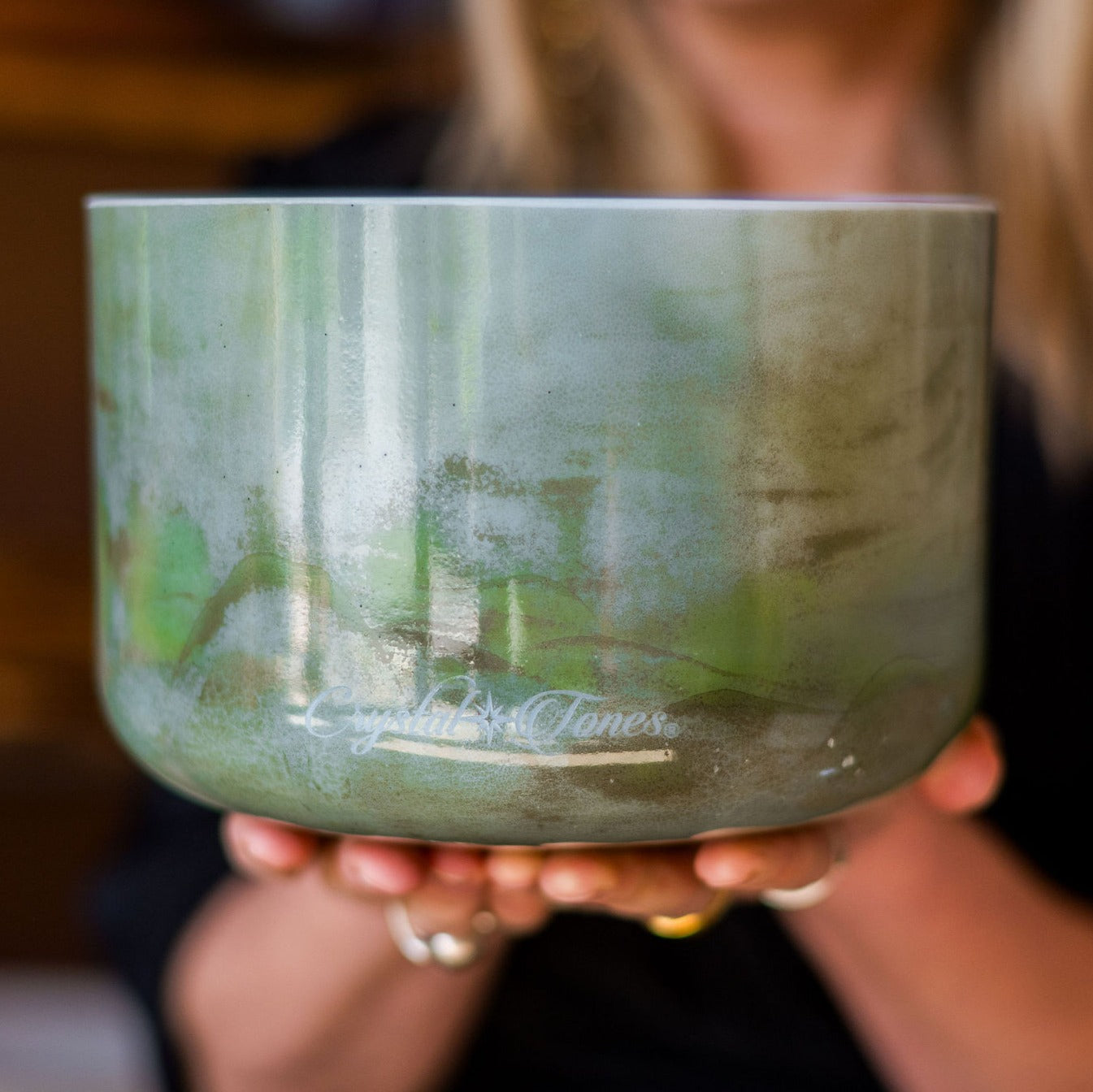 Person holding a green crystal sound bowl with 'Crystal Tones' branding.