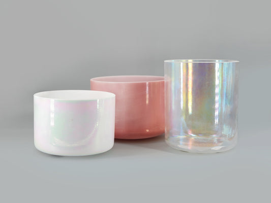 Three crystal sound bowls with iridescent finishes on a gray background
