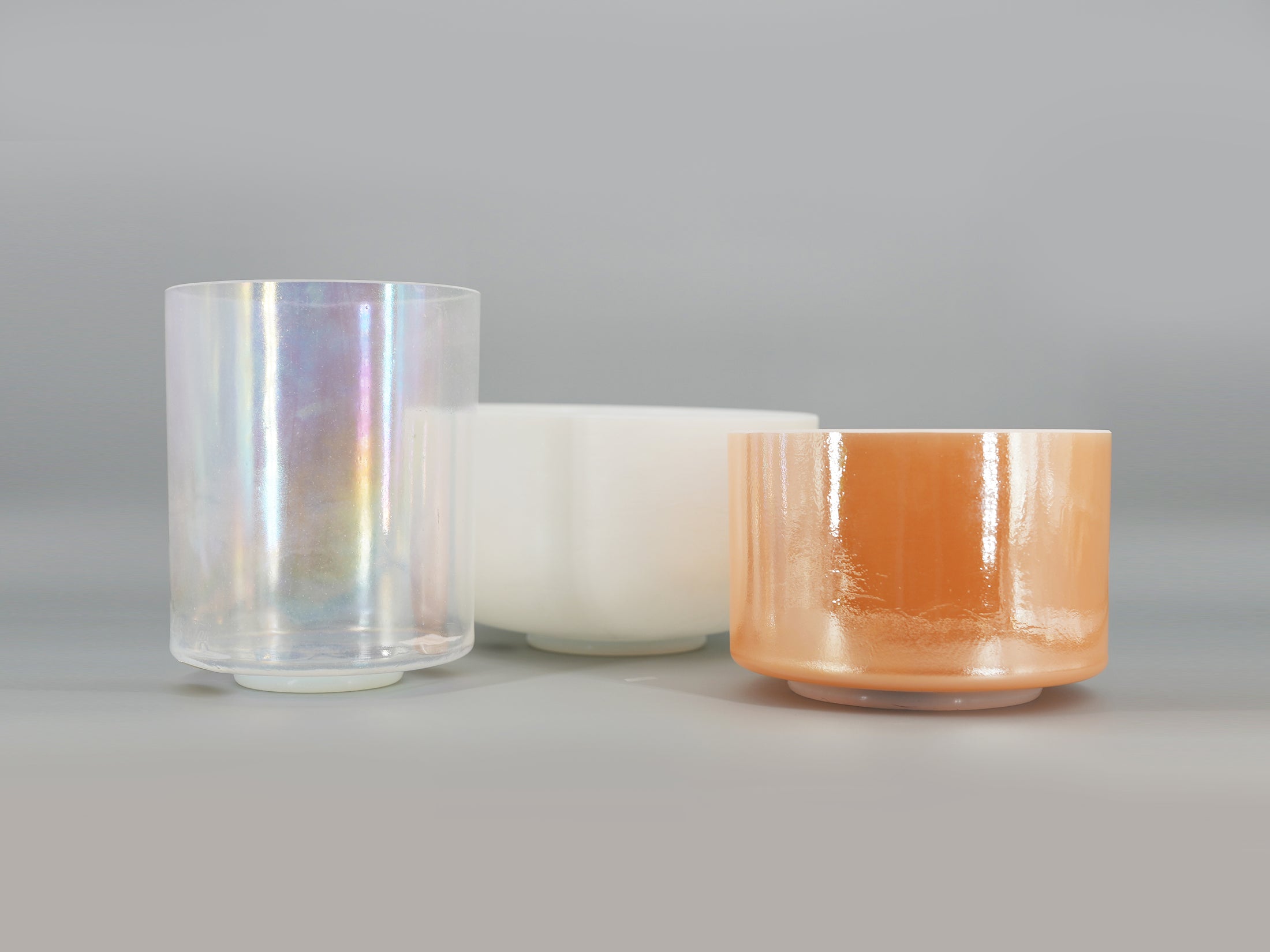 Three crystal sound bowls in different colors on a gray background