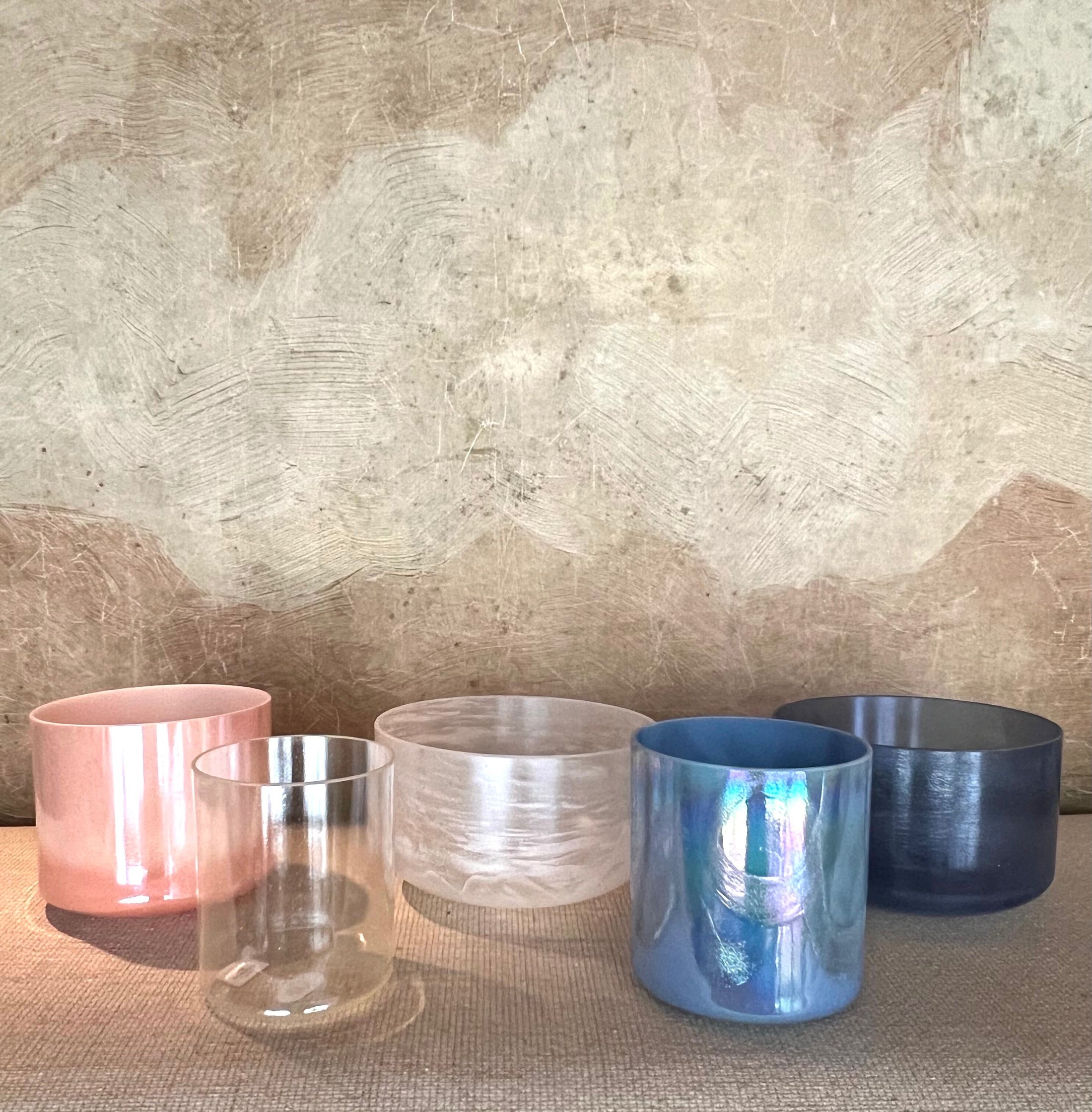 Set of five metallic-colored Crystal Sound Bowls on a textured surface with a neutral background