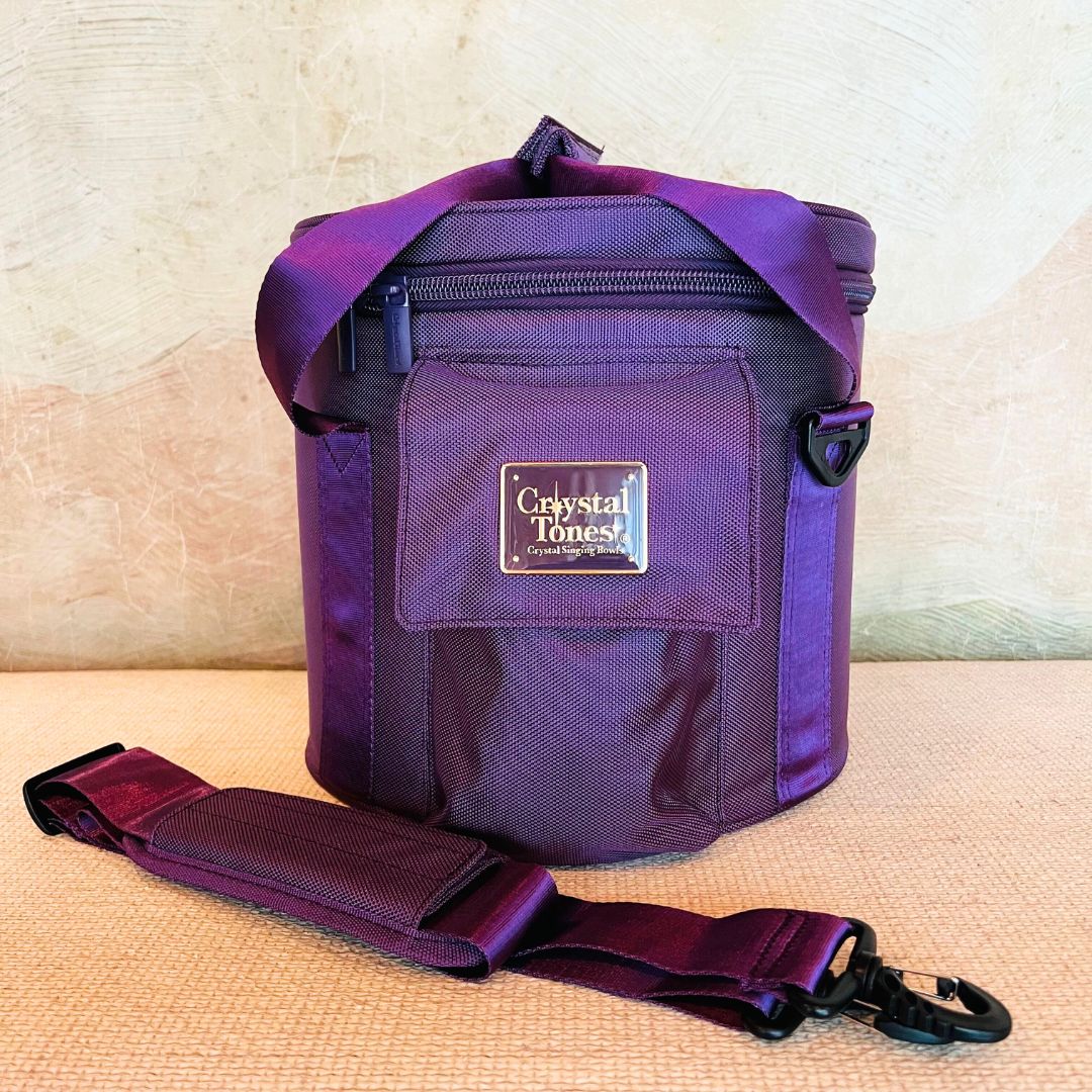Purple crystal sound bowl carry case with a visible brand Crystal Tones logo on a beige surface