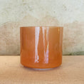 Load image into Gallery viewer, Orange crystal sound bowl on a textured surface with a neutral background
