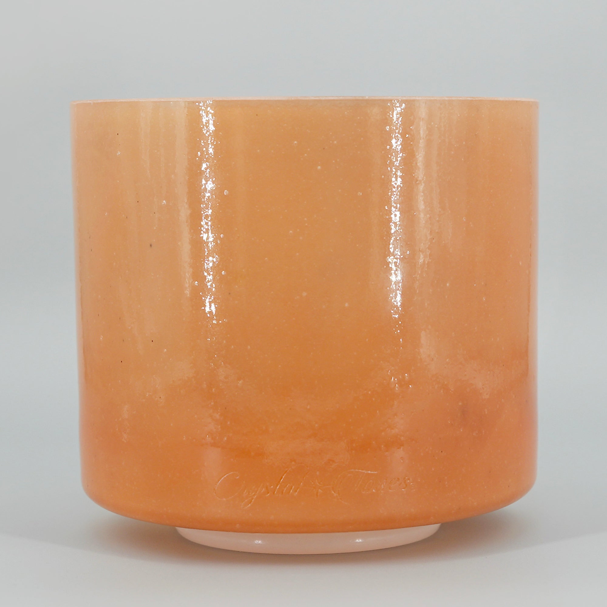 Cylindrical crystal sound bowl with a glossy finish on a gray background