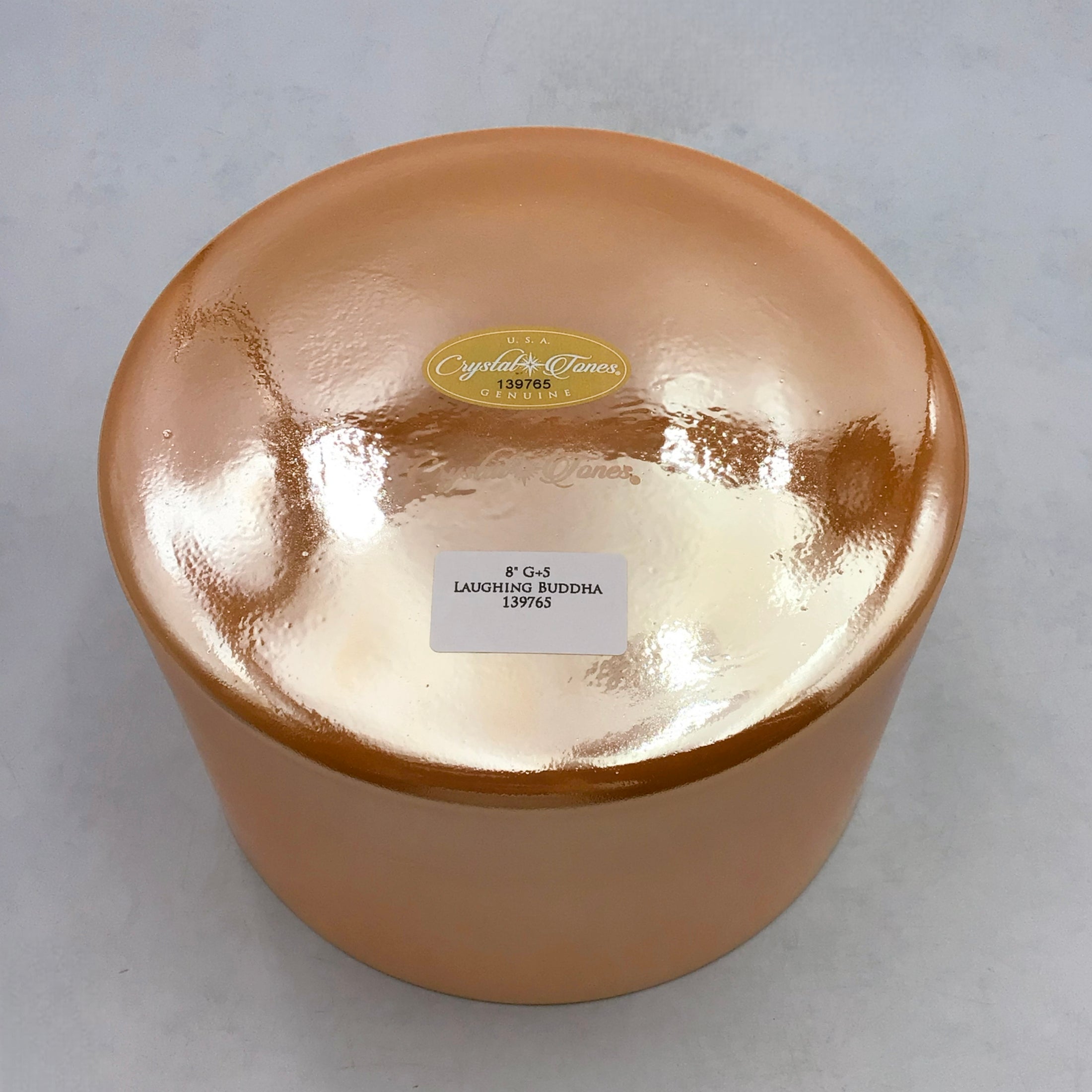 View of the base of an orange Crystal sound bowl with two lables 