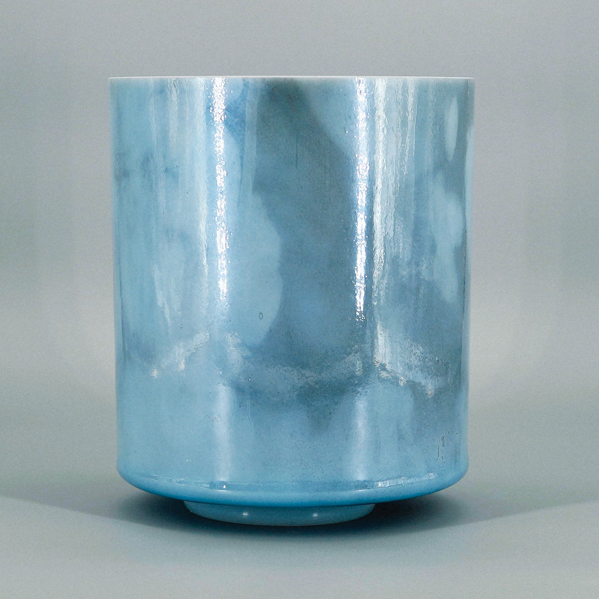 Blue crystal sound bowl with marbled pattern on a gray background
