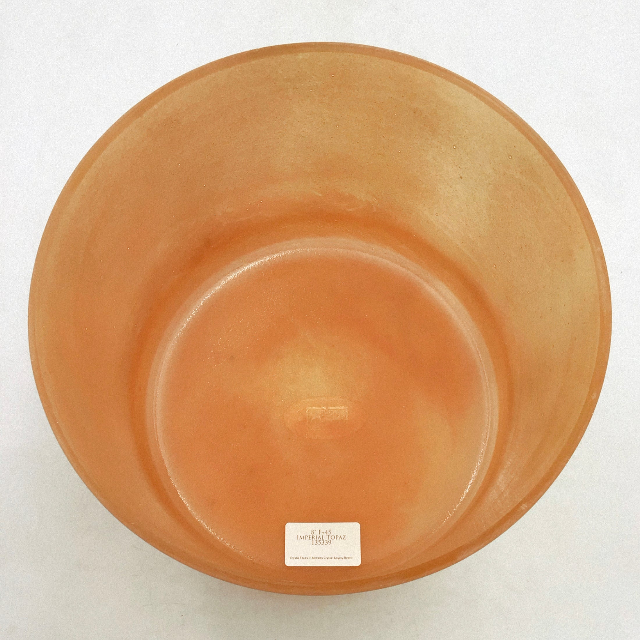 Inside view of a crystal sound bowl with a visible brand label on a white background