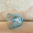 Load image into Gallery viewer, Teal crystal sound bowl with geometric design on a textured beige surface
