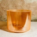 Load image into Gallery viewer, Copper-colored crystal sound bowl with 'Crystal Tones' branding on a textured surface.
