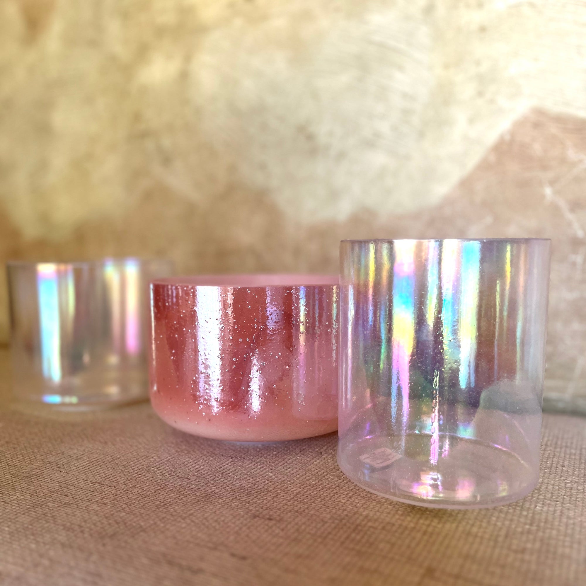 Iridescent crystal sound bowls on a textured surface with a blurred background