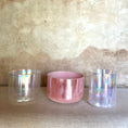 Load image into Gallery viewer, Three crystal sound bowls with iridescent and pink finishes on a textured surface.

