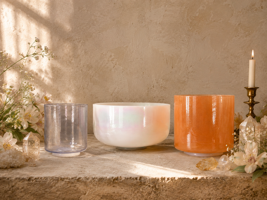 Dream Manifest Harmonised Set of three Crystal Tones® singing bowls on plaster background with flowers, crystals and lit candle