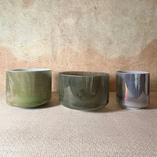 Earthsong harmonised Crystal Tones® Alchemy™ bowl set with green Chrysoprase, Itoigawa Jade and reflective Charcoal Palladium bowls, arranged on a textured beige mat.